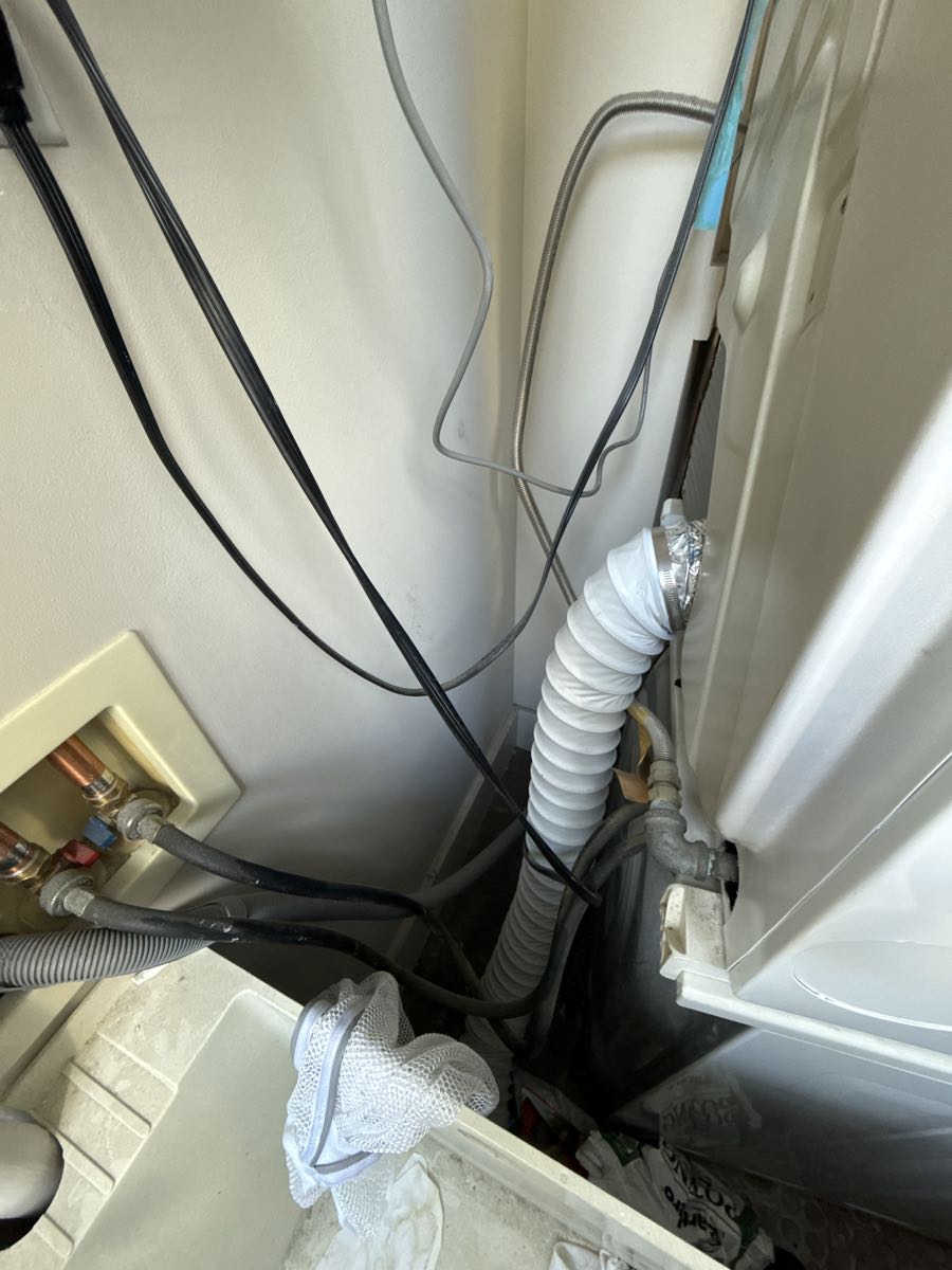 Before photo showing long Mylar flexible dryer transition duct approximately 9 feet in length connecting dryer to wall outlet