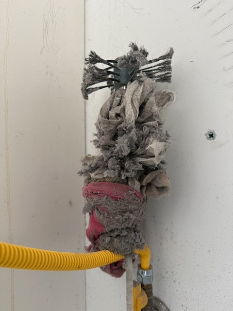 Underwear and socks pulled out of a dryer drum and lodged inside a dryer vent duct, blocking airflow