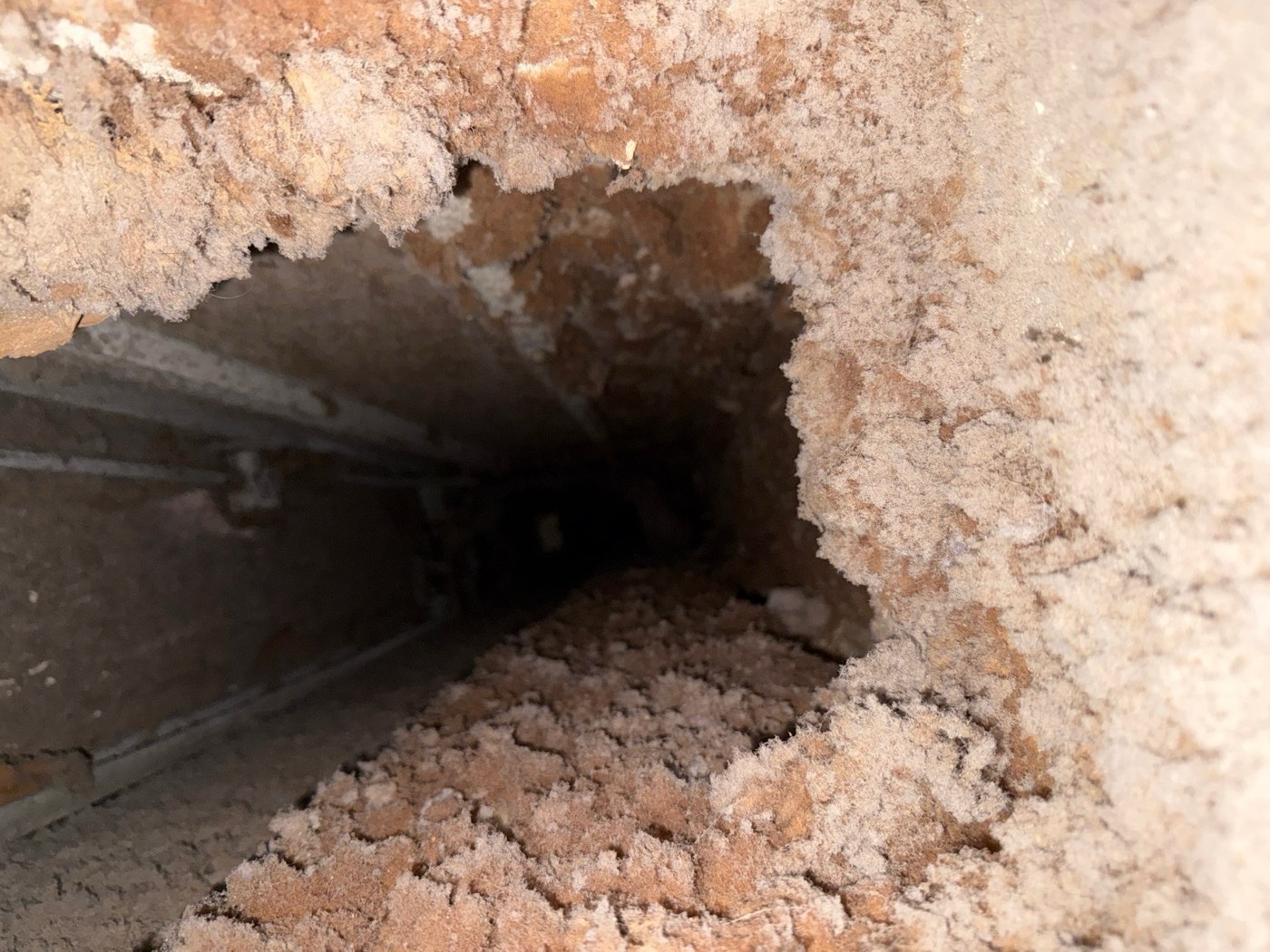 Inside a dryer vent duct shaft showing thick lint buildup coating all interior surfaces